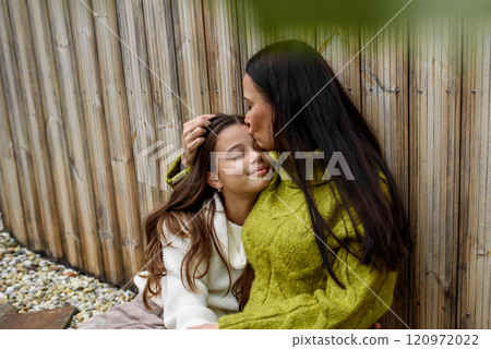 Portrait of beautiful mother with young daughter, sitting together and embracing. Portrait of beautiful mother with young daughter, sitting together and embracing. 120972022