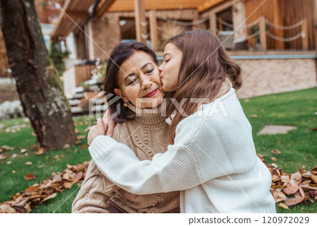 Young granddaughter kissing her grandmother on cheek, enjoying ttime together. Young granddaughter kissing her grandmother on cheek, enjoying ttime together. 120972029