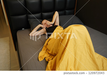 A woman sleeping peacefully under a yellow blanket A woman sleeping peacefully under a yellow blanket 120972043