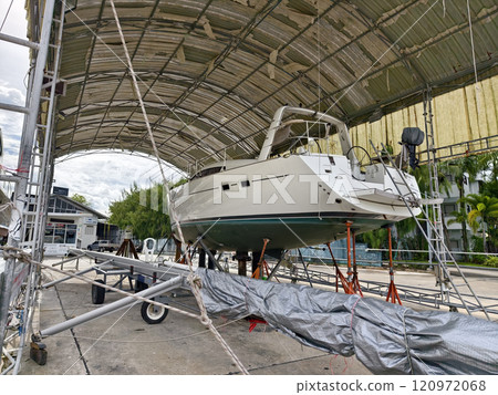 A boat is carefully lifted under a covered structure A boat is carefully lifted under a covered structure 120972068