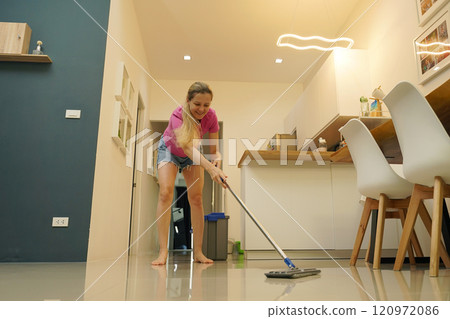 A woman is cleaning her living room at home 120972086
