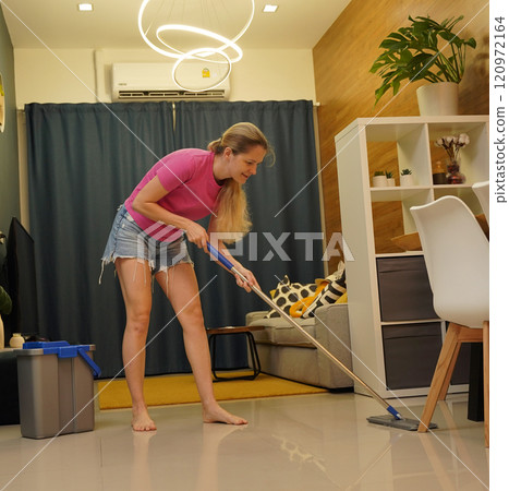 A woman is cleaning her living room at home 120972164
