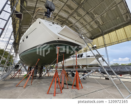 A boat is carefully lifted under a covered structure A boat is carefully lifted under a covered structure 120972165