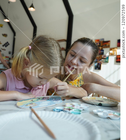 A young mother and her daughter enjoy a creative art session at home A young mother and her daughter enjoy a creative art session at home 120972599