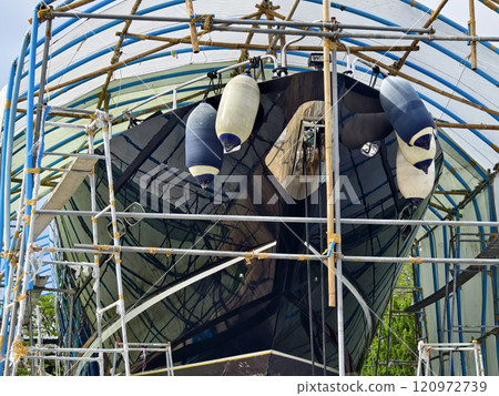 A boat is carefully lifted under a covered structure 120972739