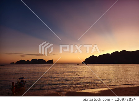 A stunning sunset is casting vibrant hues of color over a tranquil ocean 120972854