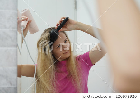 A woman is expertly styling her hair using a blow dryer and brush while in the bathroom 120972920