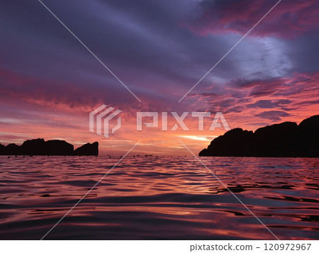 A stunning sunset is casting vibrant hues of color over a tranquil ocean A stunning sunset is casting vibrant hues of color over a tranquil ocean 120972967