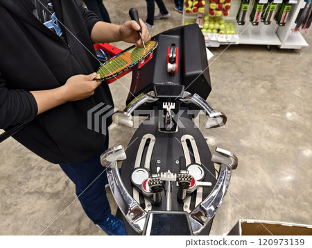 Strings a badminton racket on a racket stringing machine. 120973139