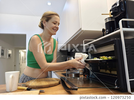 A young woman joyfully prepares a variety of healthy meals  120973250