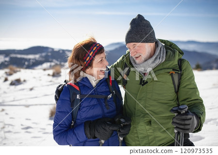 Portrait of active seniors enjoying winter nature. Romantic winter hike for an elderly couple in snowy mountains. 120973535