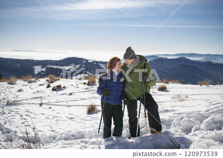 Portrait of active seniors enjoying winter nature. Romantic winter hike for an elderly couple in snowy mountains. Portrait of active seniors enjoying winter nature. Romantic winter hike for an elderly couple in snowy mountains. 120973539