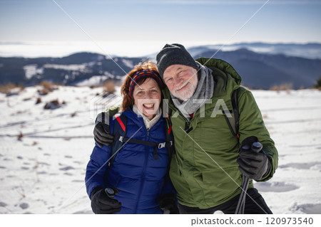 Portrait of active seniors enjoying winter nature. Romantic winter hike for an elderly couple in snowy mountains. 120973540