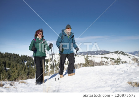 Active seniors enjoying winter nature. Romantic winter hike for an elderly couple in snowy mountains. Active seniors enjoying winter nature. Romantic winter hike for an elderly couple in snowy mountains. 120973572
