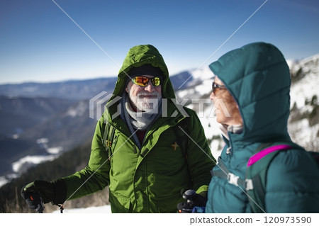 Portrait of active seniors enjoying nature. Romantic winter hike for an elderly couple in snowy mountains. Portrait of active seniors enjoying nature. Romantic winter hike for an elderly couple in snowy mountains. 120973590
