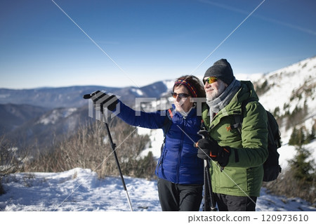 Portrait of active seniors enjoying nature. Romantic winter hike for an elderly couple in snowy mountains. 120973610