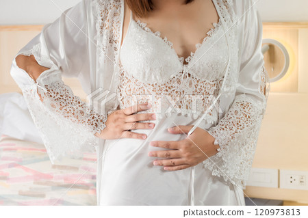 A woman in a nightgown experiences severe menstrual cramps at night. 120973813