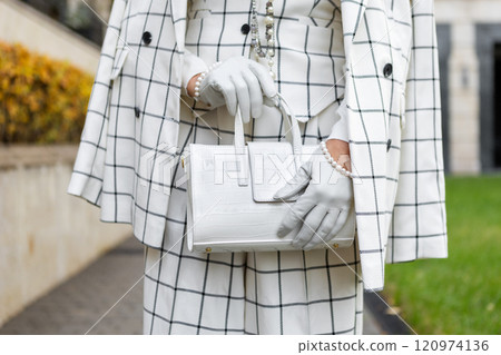 Fashionable Woman Outside in City Dressed in Stylish Checkered Suit with Blazer and Trousers, White Handbag, Showcasing Details Trendy Clothing and Street Style 120974136