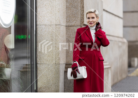 Portrait Stylish Woman in Burgundy Coat in City Street Wearing Fashionable clothing White Turtleneck Sweater, Grey Jeans, Carrying White Bag. Confident and Chic Mature Fashion Model Portrait Stylish Woman in Burgundy Coat in City Street Wearing Fashionable clothing White Turtleneck Sweater, Grey Jeans, Carrying White Bag. Confident and Chic Mature Fashion Model 120974202