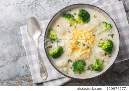 Spicy creamy broccoli gnocchi soup with cheddar cheese, thyme, onion and garlic close-up in a plate. Horizontal top view Spicy creamy broccoli gnocchi soup with cheddar cheese, thyme, onion and garlic close-up in a plate. Horizontal top view 120974277
