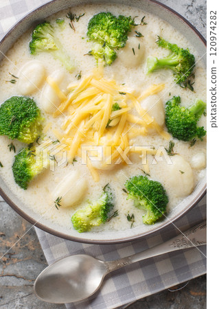 Classic broccoli cheese soup with tender gnocchi closeup on the plate on the table. Vertical top view 120974282