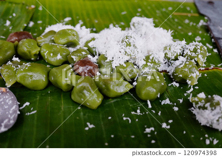 Klepon Tanah Lot is Indonesian traditional food or dessert made of sweet rice powder filled with coconut crumble and brown sugar on banana leaf. Street food in Bali Klepon Tanah Lot is Indonesian traditional food or dessert made of sweet rice powder filled with coconut crumble and brown sugar on banana leaf. Street food in Bali 120974398