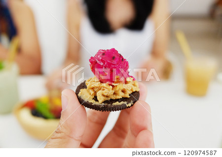 Close up on woman hand holding homemade chocolate biscuits with dragon fruit and nut cream in cafe Close up on woman hand holding homemade chocolate biscuits with dragon fruit and nut cream in cafe 120974587