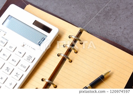 Image of working at a desk with a calculator and notebook Image of working at a desk with a calculator and notebook 120974597