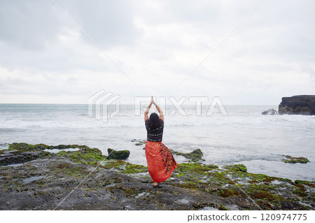 Asian woman wearing native Sarong of Bali doing yoga poses on the coast of the Indian Ocean at Bali Island of Indonesia. Travel destination and freedom life of Asian concept Asian woman wearing native Sarong of Bali doing yoga poses on the coast of the Indian Ocean at Bali Island of Indonesia. Travel destination and freedom life of Asian concept 120974775