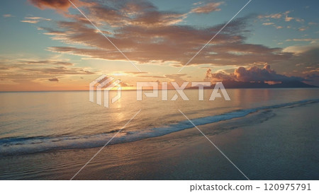 Golden sunset illuminate tranquil ocean, Moorea island in background, tropical paradise scene in French Polynesia. Colorful orange cloudy sky reflect in sea waves. Exotic summer travel. Aerial flight 120975791