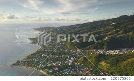 Stunning aerial view panorama of Punaauia city nestled between lush green mountains hills canyon and turquoise pacific ocean lagoon. Tahiti tropical island in sunset glow. Explore French Polynesia 120975805