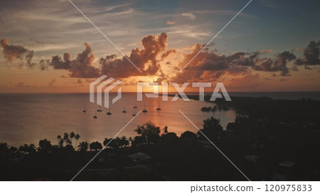 Aerial view of sailboats near a tropical island in Rangiroa, French Polynesia at sunset, with golden light over calm waters and dramatic clouds. Remote wild nature paradise, exotic summer travel 120975833