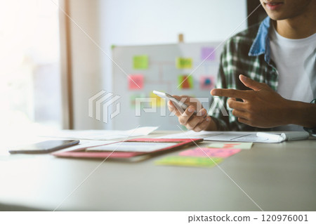 Male designer working on app development, using smartphone and sketches to refine user interface Male designer working on app development, using smartphone and sketches to refine user interface 120976001