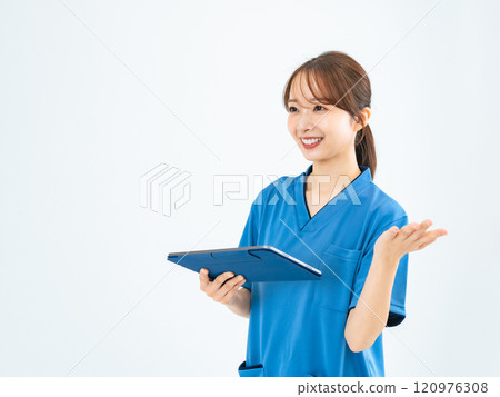 一位穿著手術服的女士拿著平板電腦說話 一位穿著手術服的女士拿著平板電腦說話 120976308