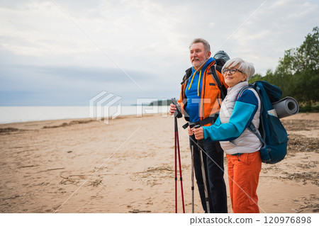 Hiking tourism adventure. Senior couple man woman enjoying outdoor recreation hiking on beach. Happy old people backpackers hikers enjoy walking hike trekking tourism active vacation beauty of nature 120976898