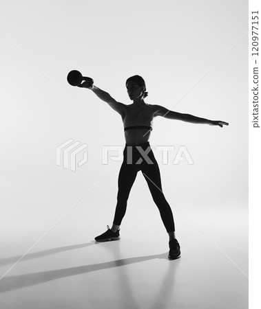 Black and white photography. Full-length image of young woman with slim body, training, doing exercises with kettlebell 120977151