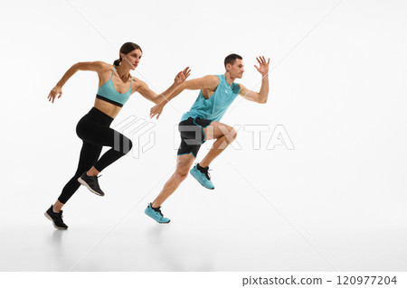 Full-length dynamic image of young athletic couple, man and woman in motion, running against white studio background Full-length dynamic image of young athletic couple, man and woman in motion, running against white studio background 120977204