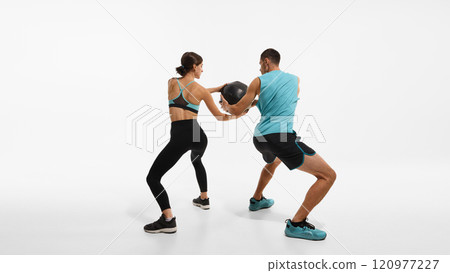 Sportive couple, young man and woman in sportswear training together, doing exercises with medicine ball against white studio background 120977227