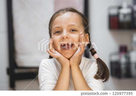 Portrait of little Caucasian girl showing missing baby teeth with joyful expression in bathroom. Concept of childhood milestones and happiness. Portrait of little Caucasian girl showing missing baby teeth with joyful expression in bathroom. Concept of childhood milestones and happiness. 120977395