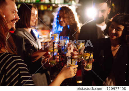 Cheering and drinking cocktails. Group of friends partying in nightclub, toasting drinks cocktails. 120977408