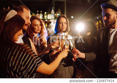 Cheering and drinking cocktails. Group of friends partying in nightclub, toasting drinks cocktails. 120977414