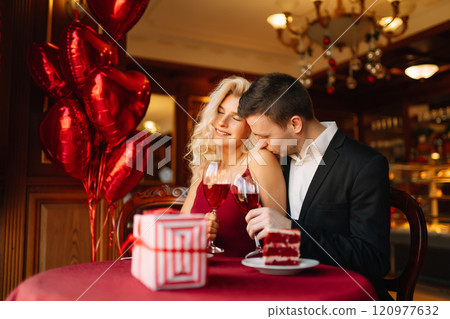 Young couple having a romantic dinner and toasting with glass of red wine. Surprise and love concept 120977632