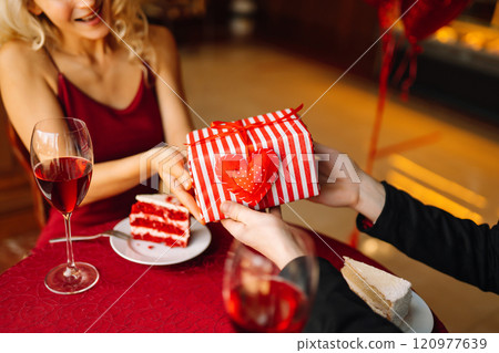 Couple in love exchanges gifts. Handsome man and woman on a date in a restaurant. Concept of love. 120977639