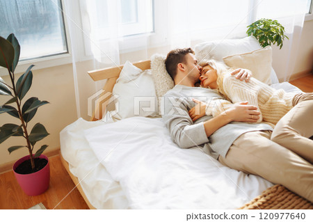 Couple in love relaxing at home on the bed while they hug each other and having fun. Valentine's Day Couple in love relaxing at home on the bed while they hug each other and having fun. Valentine's Day 120977640