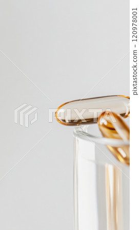 Close-up of omega-3 fish oil capsules in a glass container for health and wellbeing 120978001