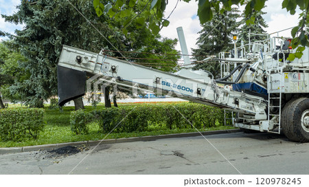 a white paver stands near the sidewalk, against the background of trees 120978245