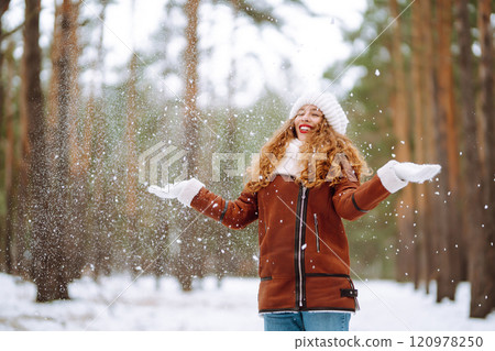 Beautiful woman standing among snowy trees and enjoying first snow. Holidays, rest, travel concept. 120978250