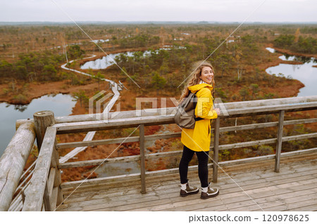 Young woman looks at amazing nature on observation deck. Tourist enjoys a view of magical swamps. 120978625
