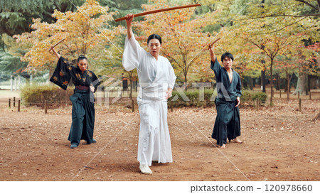 Martial arts, people and instructor with wood sword for fight, battle and samurai training class. Park, ninja and mentor with bamboo weapon, kendo and warrior in autumn in Japan with fighter group 120978660