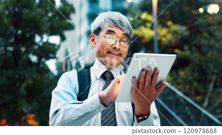 Outdoor, businessman and smile with tablet on website for stock exchange rates in Japan. Mature person, city and happy as employee in finance on internet or app for market share or investment returns 120978688